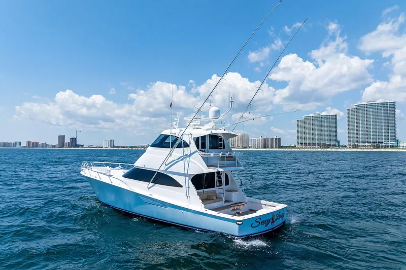 Slide: The Image of 2017 Viking 62 Enclosed Bridge yacht cruising near coastal city skyline. - 5