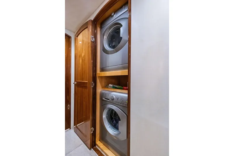 Slide: The Image of Laundry area with stacked washer and dryer in 2017 Viking 62 Enclosed Bridge yacht. - 53