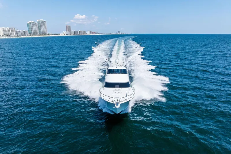 Slide: The Image of 2017 Viking 62 Enclosed Bridge yacht cruising on open ocean near city skyline. - 68