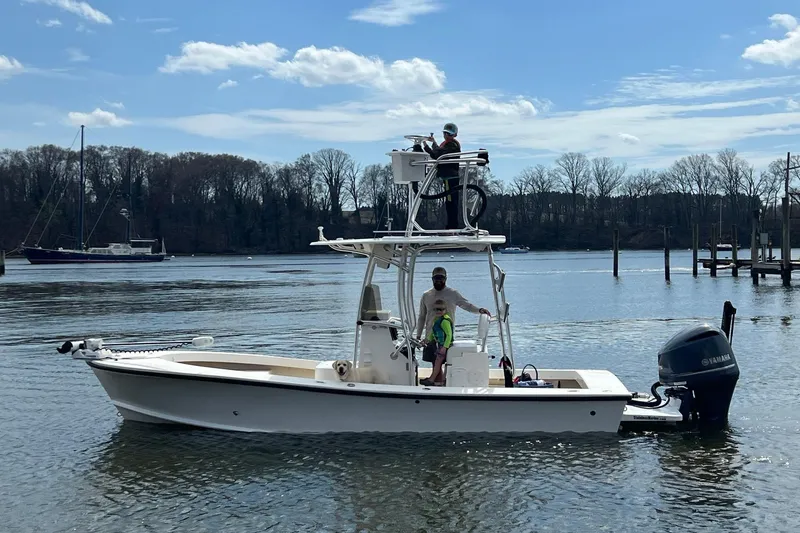 Slide: The Image of 2014 Privateer ROAMER II boat on calm water with people onboard, scenic background. - 2