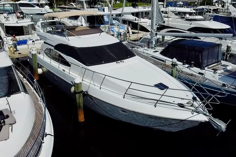 The Image of 1999 Azimut 58 yacht docked in a marina, surrounded by other boats. - 0