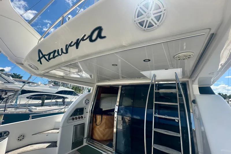 Slide: The Image of 1999 Azimut 58 yacht with "Azzurra" name, featuring sleek design and ladder access. - 19