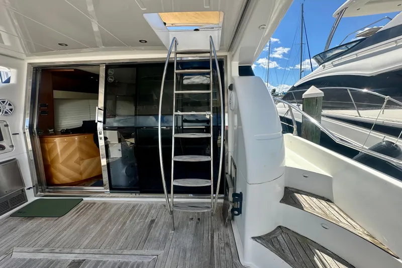 Slide: The Image of 1999 Azimut 58 yacht interior with wooden flooring and metal staircase, docked at marina. - 20