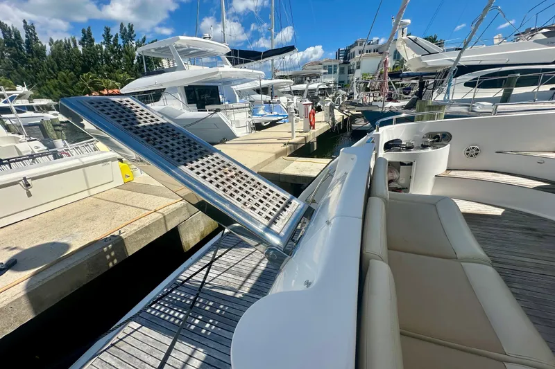 Slide: The Image of 1999 Azimut 58 yacht docked, featuring a gangway and luxurious seating area. - 28