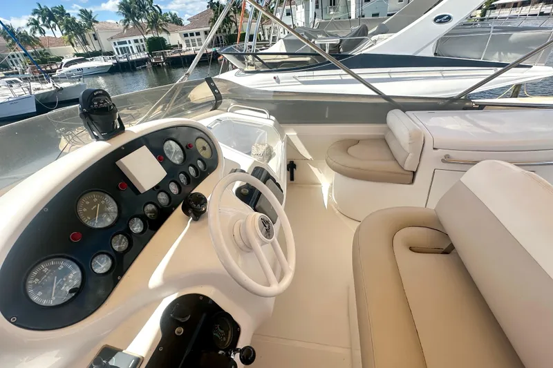 Slide: The Image of 1999 Azimut 58 yacht cockpit with steering wheel, gauges, and seating, docked at marina. - 34