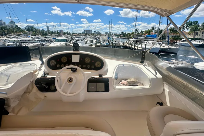 Slide: The Image of Cockpit view of a 1999 Azimut 58 yacht docked at a marina under a sunny sky. - 35