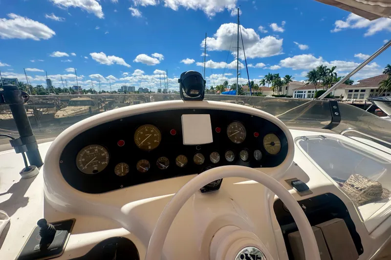 Slide: The Image of Cockpit view of a 1999 Azimut 58 yacht with clear blue skies and marina backdrop. - 38