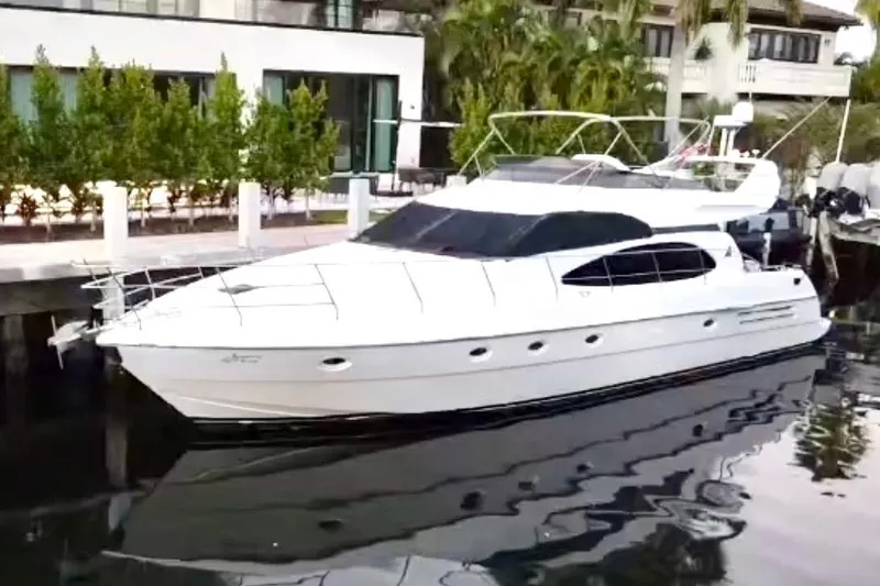 Slide: The Image of 1999 Azimut 58 yacht docked by waterfront, showcasing sleek design and luxury features. - 4