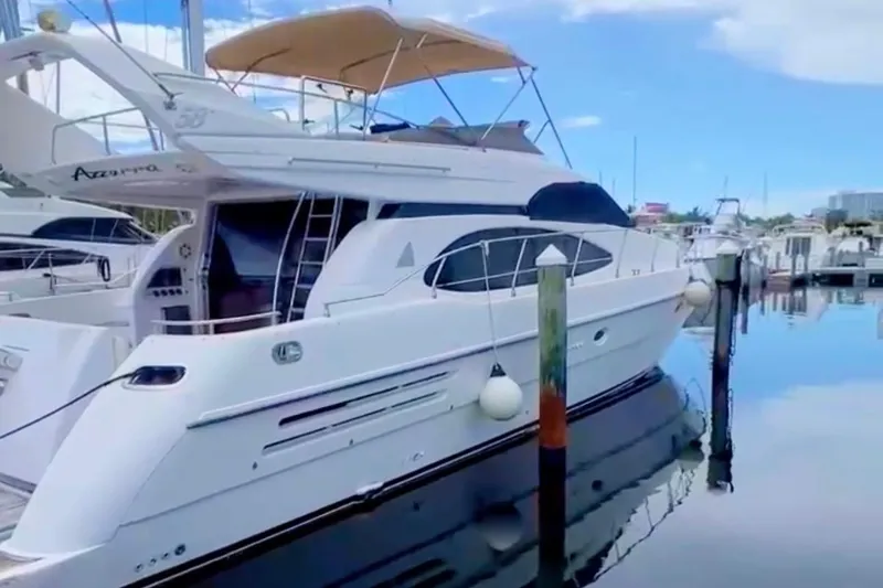 Slide: The Image of Luxury 1999 Azimut 58 yacht docked at marina under clear blue sky. - 5