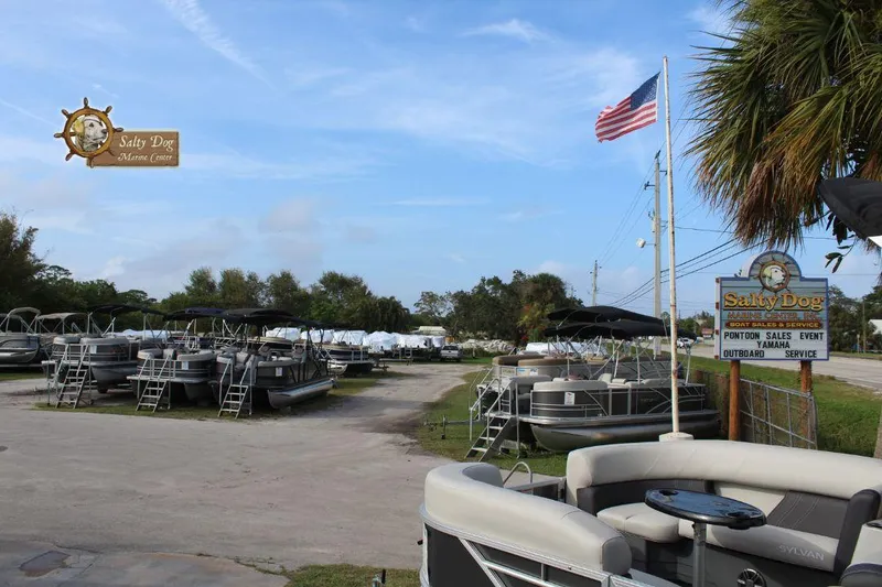 Slide: The Image of 2026 Sylvan Mirage X3 pontoon boat with Yamaha 150 engine, docked outdoors. - 13