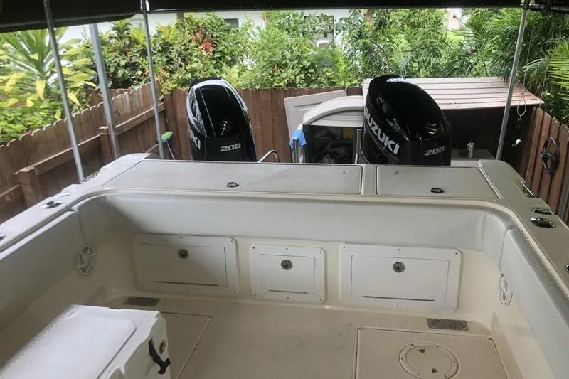 Slide: The Image of 1998 World Cat 266 SC boat with dual Suzuki 200 engines, docked near lush greenery. - 11