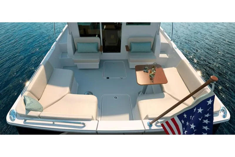 Slide: The Image of 2026 Back Cove 412 boat cruising near a rocky shoreline with buildings in the background. - 2