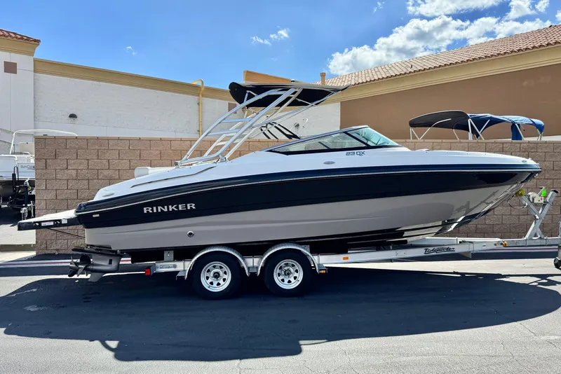 The Image of 2018 Rinker 23QX BR boat on trailer, parked outdoors under a clear sky. - 0