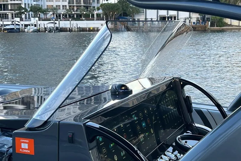 Slide: The Image of 2019 Midnight Express 43 Open boat dashboard with modern controls, docked by waterfront buildings. - 16