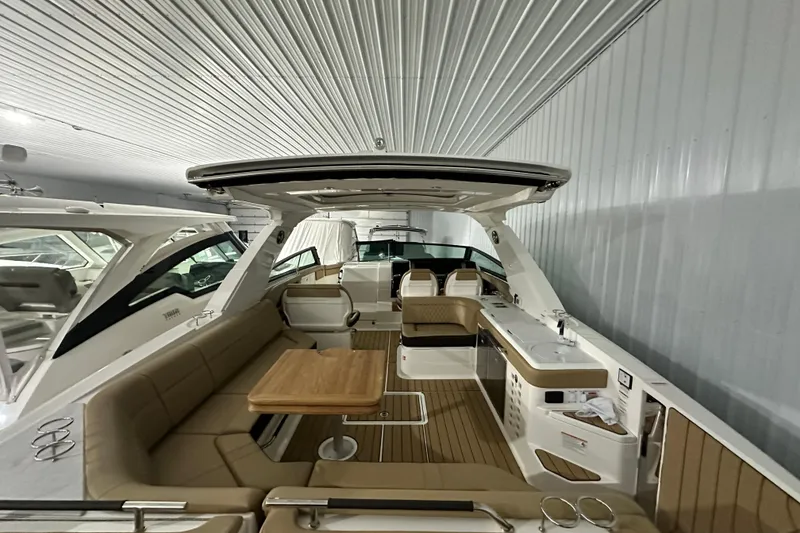 Slide: The Image of 2026 Sea Ray SLX 400 boat interior with seating, table, and kitchenette in a showroom. - 16