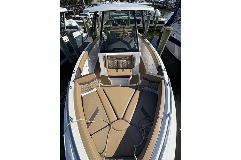 Slide: The Image of 2026 Monterey Elite 30 OB boat with luxurious tan seating at a marina. - 2
