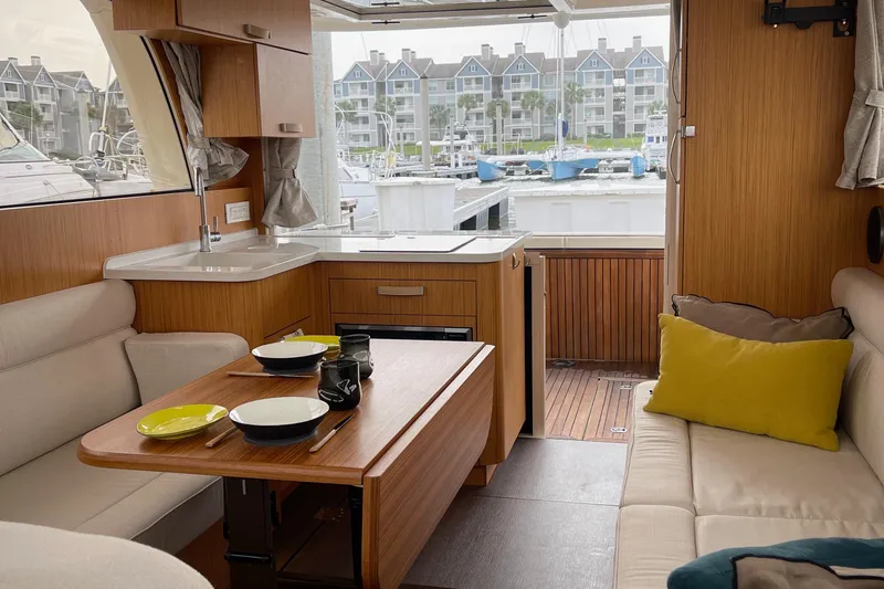 Slide: The Image of 2019 Greenline 33 Hybrid yacht interior with cozy seating, dining table, and marina view. - 13
