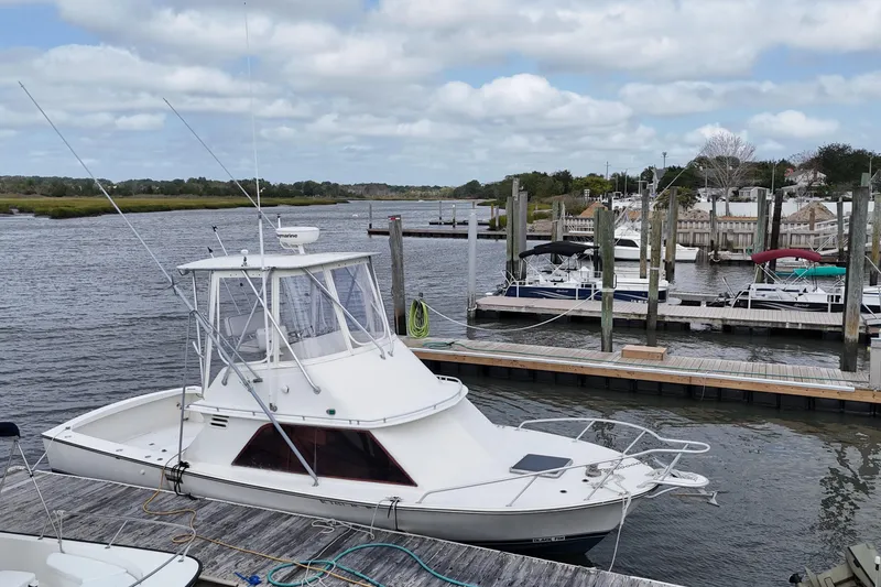 Slide: The Image of 1985 Blackfin 32 Flybridge docked at a marina under a cloudy sky. - 11