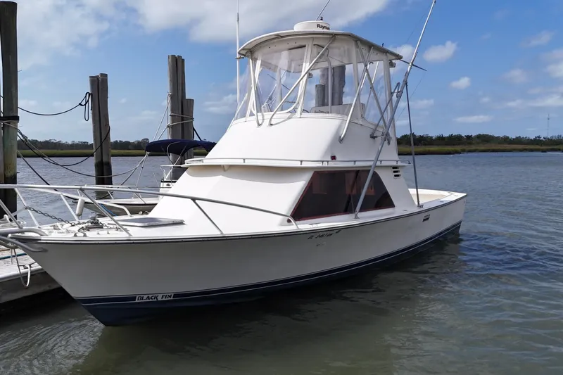 Slide: The Image of 1985 Blackfin 32 Flybridge boat docked on calm water under a blue sky. - 16