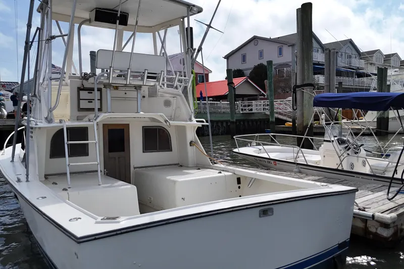 Slide: The Image of 1985 Blackfin 32 Flybridge boat docked at marina, showcasing spacious deck and flybridge. - 17