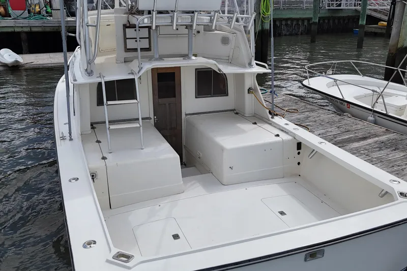 Slide: The Image of 1985 Blackfin 32 Flybridge boat docked, showcasing spacious deck and flybridge ladder. - 19