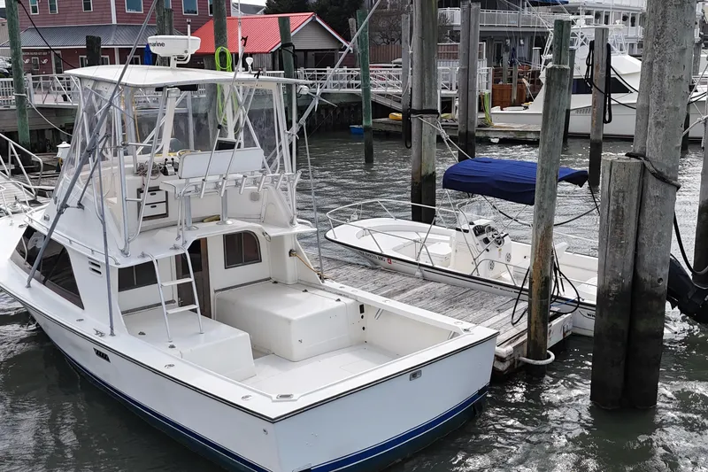 Slide: The Image of 1985 Blackfin 32 Flybridge boat docked at marina, surrounded by other vessels. - 6