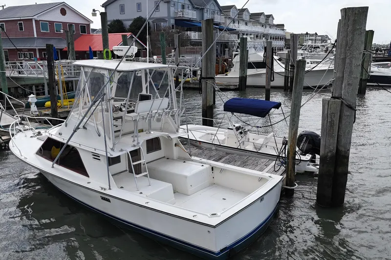 Slide: The Image of 1985 Blackfin 32 Flybridge boat docked at a marina with surrounding buildings. - 7