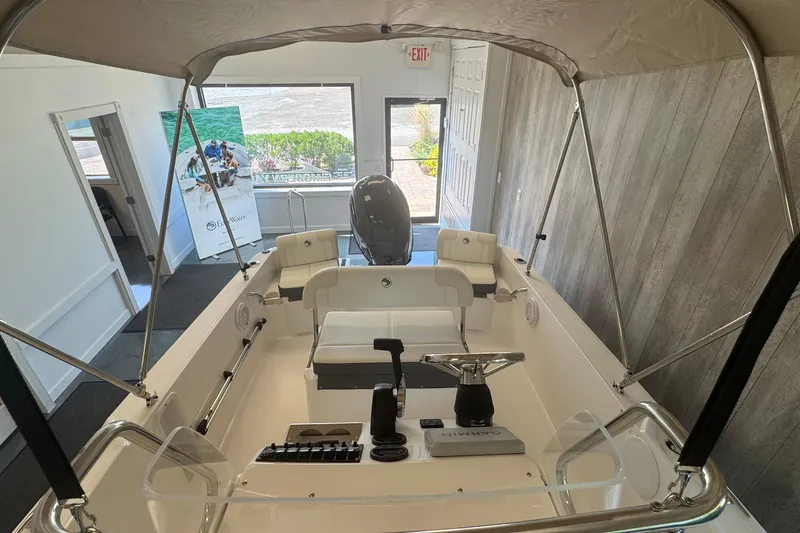 Slide: The Image of 2025 Edgewater 170CC boat interior with canopy, steering console, and seating in showroom. - 11
