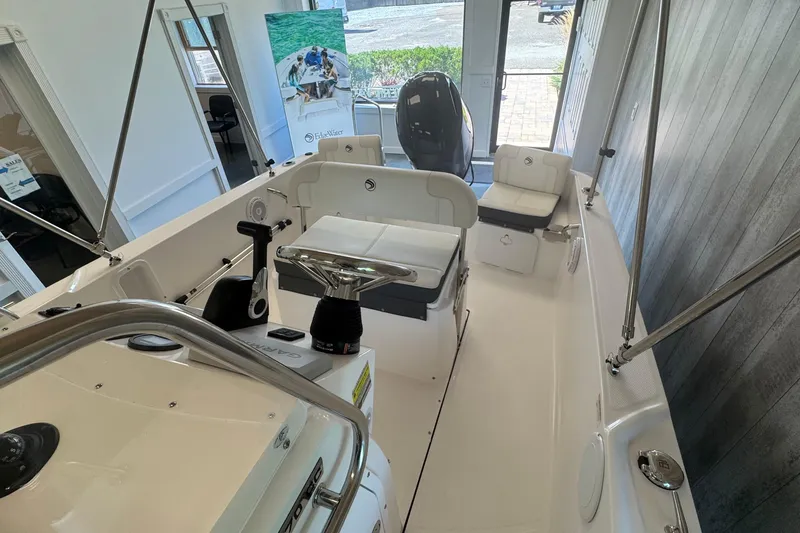 Slide: The Image of 2025 Edgewater 170CC boat interior with seating and controls, displayed in a showroom. - 12
