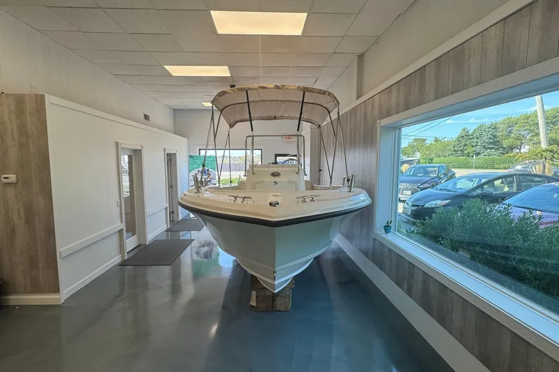 Slide: The Image of 2025 Edgewater 170CC boat displayed indoors with canopy, large window view. - 2