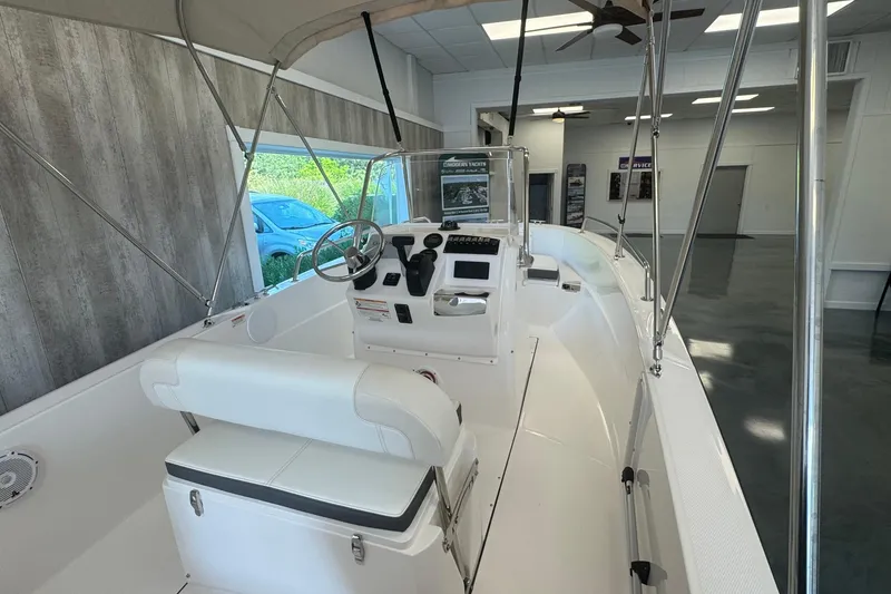 Slide: The Image of 2025 Edgewater 170CC boat interior with steering console and seating in showroom. - 9