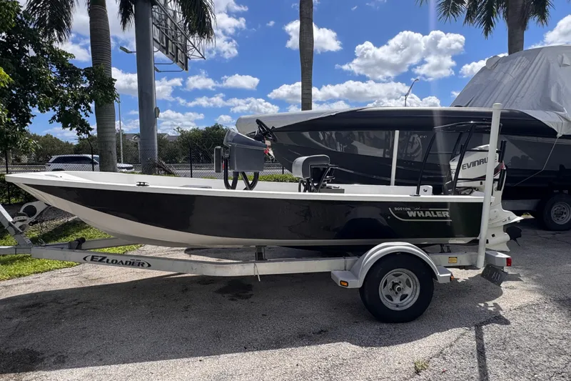 The Image of 1980 Boston Whaler 170 Montauk boat on trailer, parked outdoors under palm trees. - 0