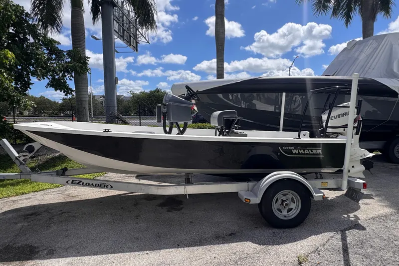 Slide: The Image of 1980 Boston Whaler 170 Montauk boat on trailer, parked outdoors under palm trees. - 13