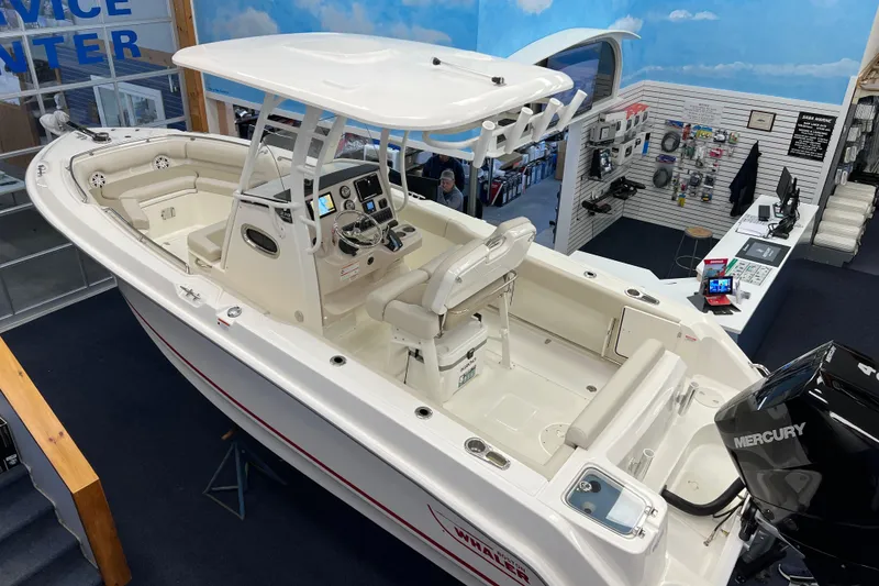 The Image of 2024 Boston Whaler 230 Outrage boat displayed indoors, featuring a Mercury engine. - 1