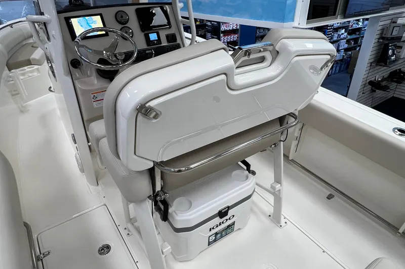 Slide: The Image of 2024 Boston Whaler 230 Outrage helm with seating and cooler storage. - 11