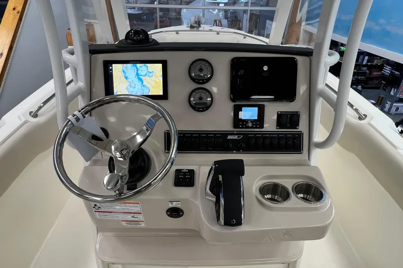 Slide: The Image of 2024 Boston Whaler 230 Outrage helm with navigation display, steering wheel, and controls. - 14