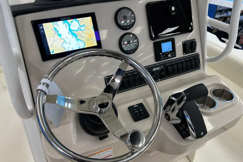 Slide: The Image of 2024 Boston Whaler 230 Outrage dashboard with steering wheel, navigation screen, and controls. - 17