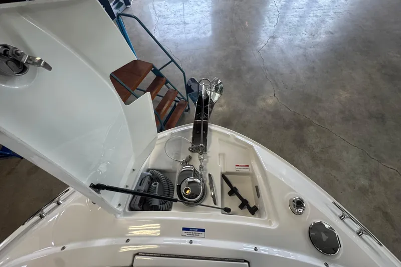 Slide: The Image of 2026 Sea Ray SLX 310 boat anchor compartment with open hatch, showcasing storage and equipment. - 16