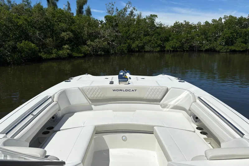 Slide: The Image of 2026 World Cat 296 DC boat with white seating, docked near lush greenery. - 16