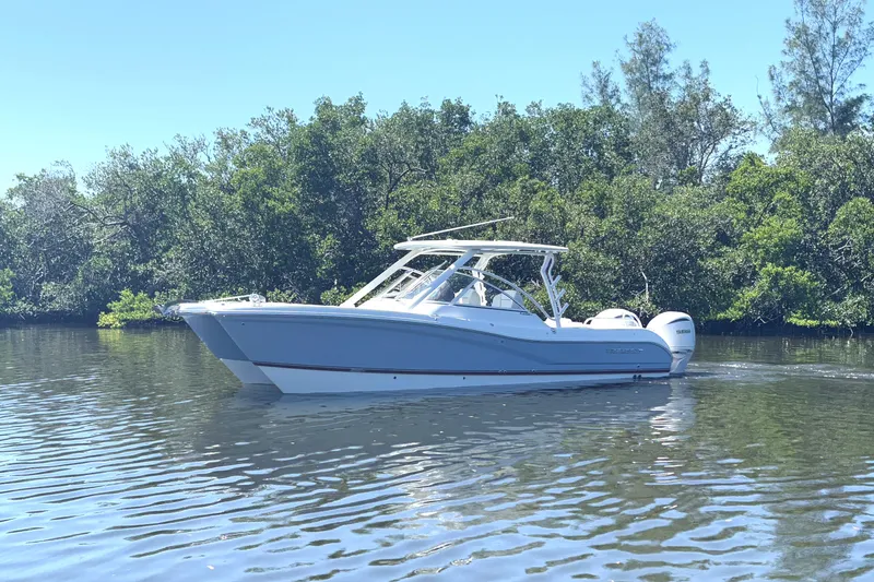 Slide: The Image of 2026 World Cat 296 DC boat cruising on a calm river, surrounded by lush greenery. - 2