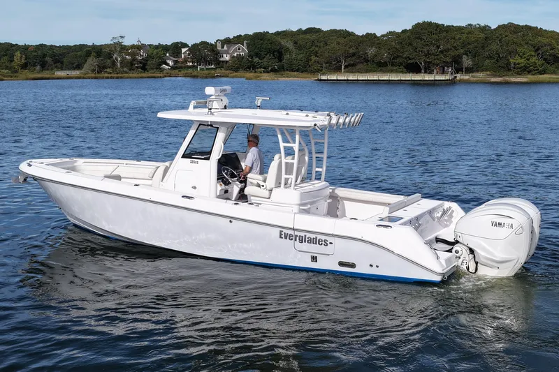Slide: The Image of 2020 Everglades 335 Center Console boat cruising on a serene lake with scenic background. - 11