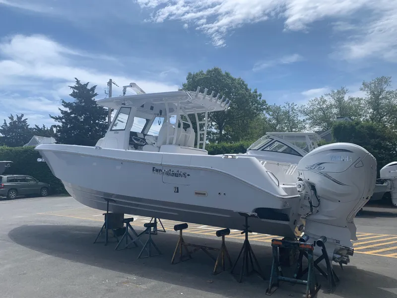 Slide: The Image of 2020 Everglades 335 Center Console boat on stands, under a partly cloudy sky. - 18