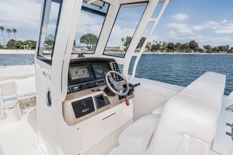 Slide: The Image of 2020 Robalo R272 Center Console boat interior with steering wheel and dashboard, on calm water. - 18