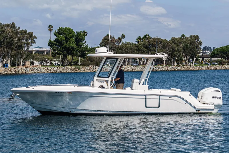 Slide: The Image of 2020 Robalo R272 Center Console boat on calm water, with trees in the background. - 5