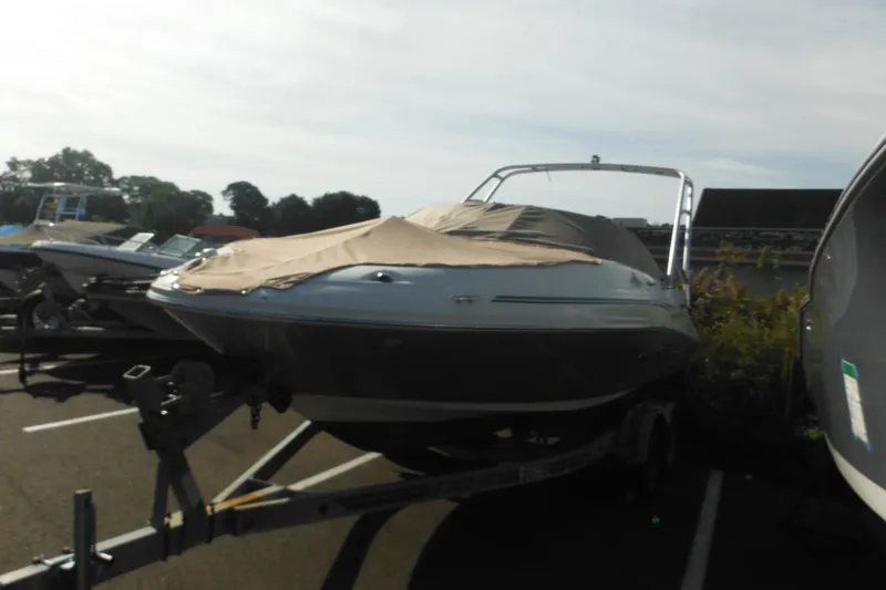 Slide: The Image of 2005 Sea Ray 220 Sundeck boat on trailer, covered and parked outdoors. - 2
