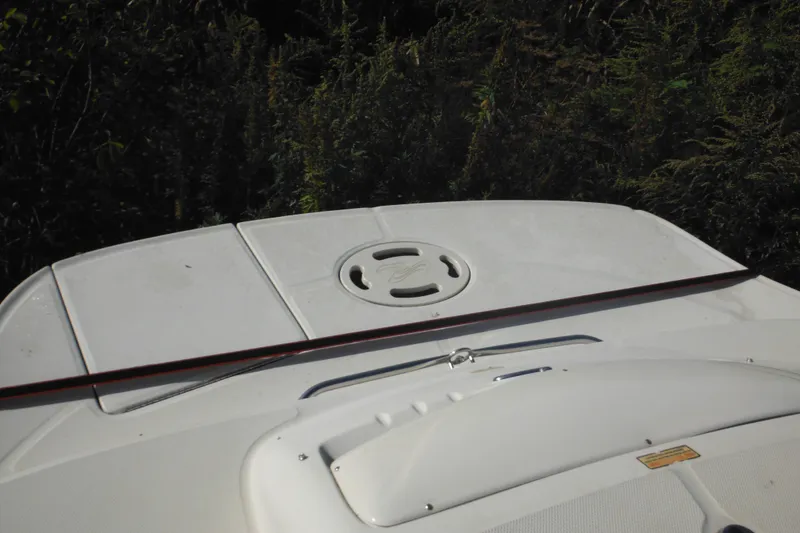 Slide: The Image of 2005 Sea Ray 220 Sundeck boat deck with hatch, surrounded by greenery. - 30