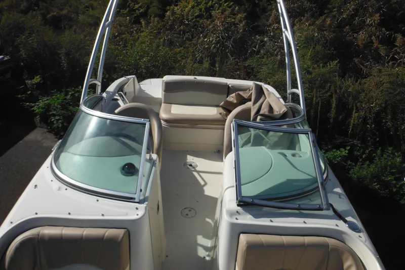 Slide: The Image of 2005 Sea Ray 220 Sundeck boat with open seating and windshield, surrounded by greenery. - 45