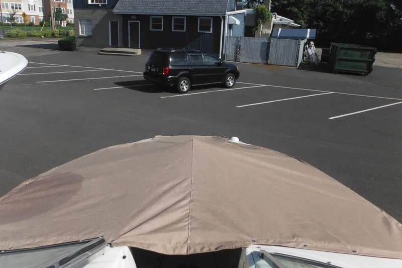 Slide: The Image of 2005 Sea Ray 220 Sundeck boat with cover in a parking lot. - 48