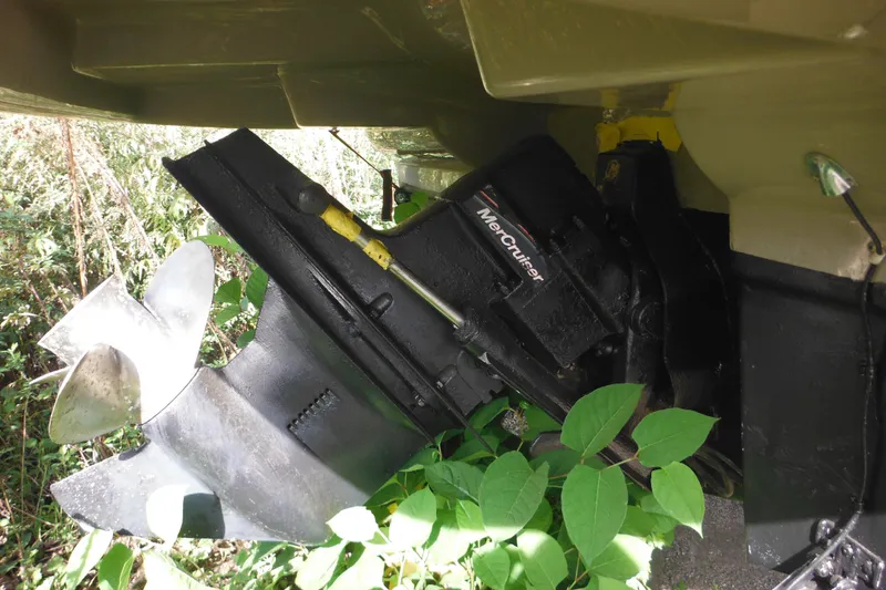 Slide: The Image of 2005 Sea Ray 220 Sundeck MerCruiser engine with propeller, surrounded by greenery. - 6