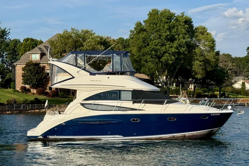 Slide: The Image of 2011 Meridian 341 Sedan yacht cruising on a serene lake near a residential area. - 2